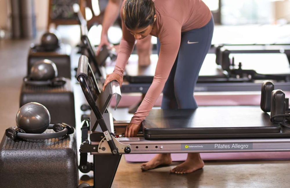 A variety of Pilates equipment including reformers and exercise accessories neatly arranged in a bright, modern studio setting.